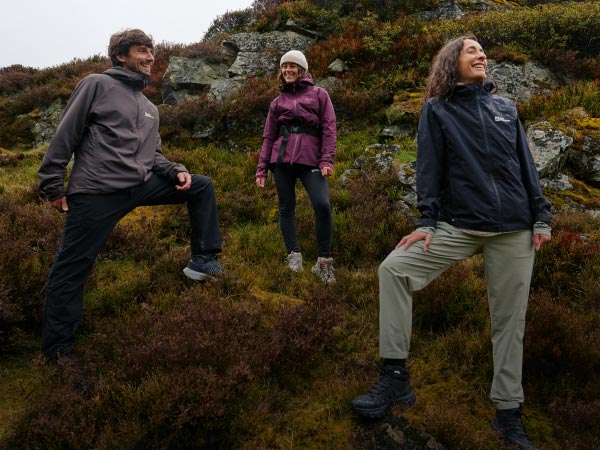 Two women in a mountain landscape, laughing while erecting a tent.