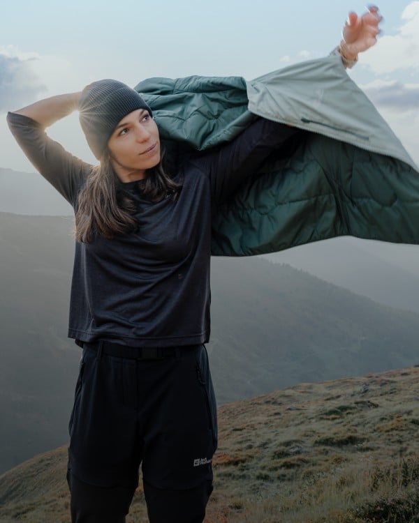 Woman in mountainous landscape puts on a jacket